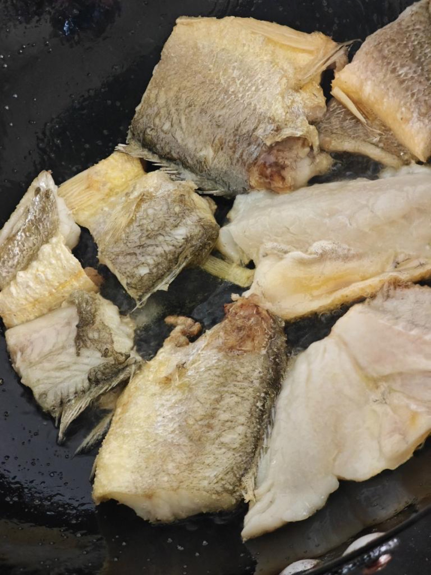 Heat the wok, add cool oil, sprinkle in a little salt to prevent sticking, and lay the fish pieces in to fry over medium-low heat.