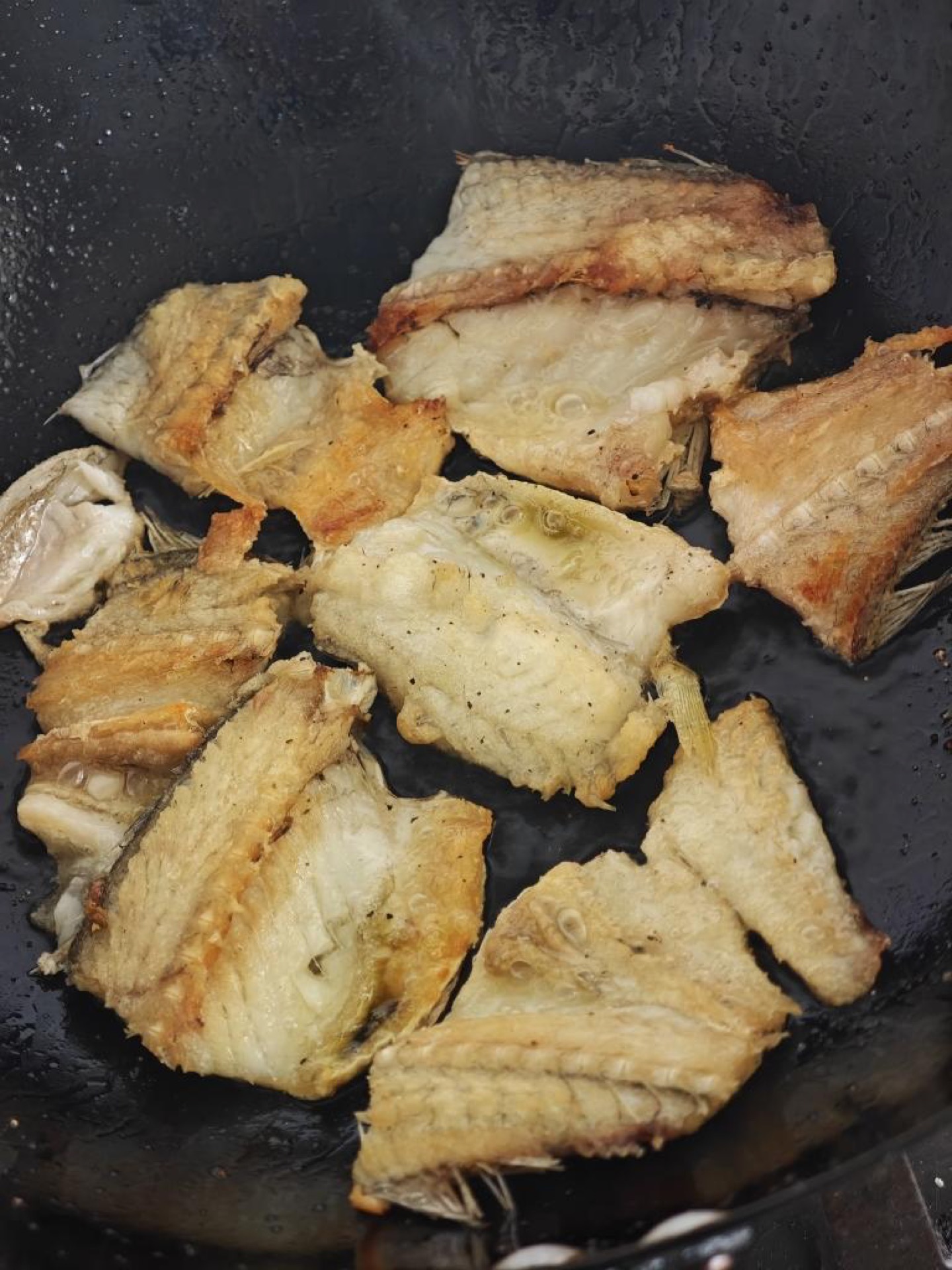 When both sides are golden brown, sprinkle on the black pepper and transfer the fish out; at this point it is crisp outside and tender inside, and it already smells wonderful.
