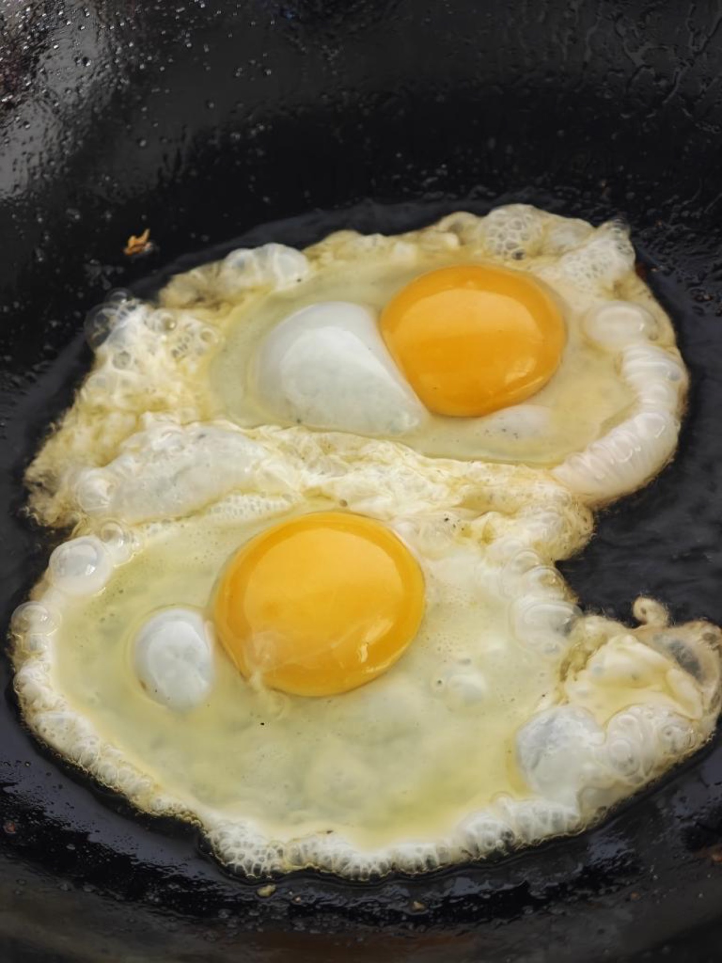 Without washing the wok, use the flavorful oil left from frying the fish to fry two eggs until the edges are crisp and the yolks are set, the old fried egg style that tastes best s