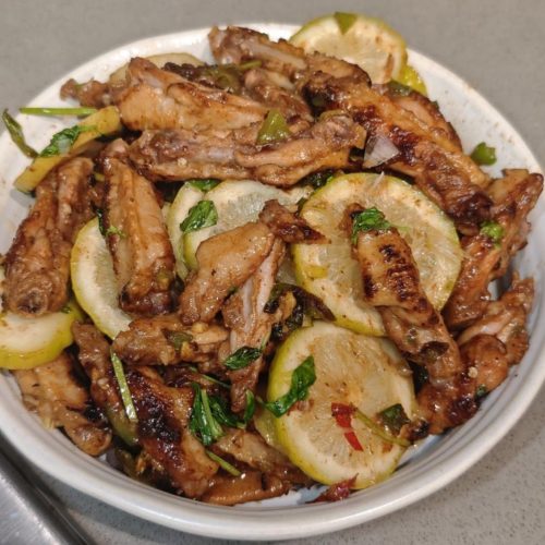 Thai lemongrass lemon chicken wings on a plate with lemon slices and basil