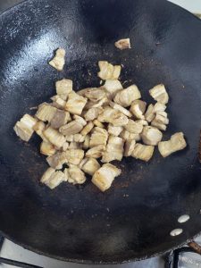 Add a little oil to the wok, tip in the sliced pork belly, and fry until the fat renders and both sides are lightly browned.