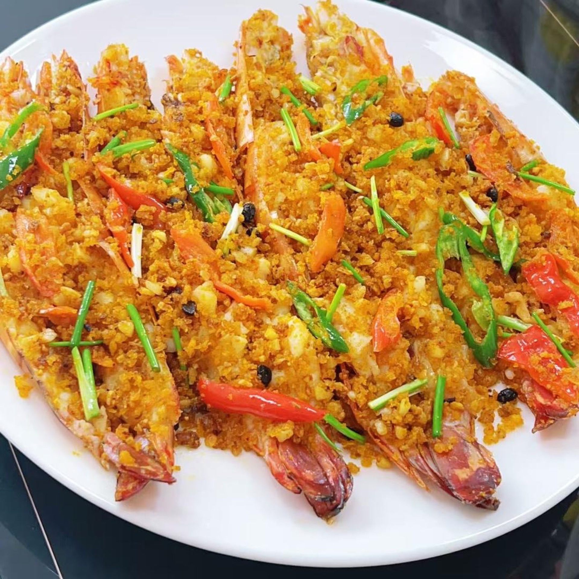 Typhoon shelter fried prawns on a plate with crispy golden garlic and chilies