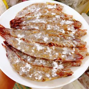 Use a small knife to score the meat in a crosshatch, cutting the connective tissue so the prawns stay straight instead of curling at high heat — this looks better plated and helps
