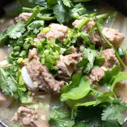 Winter melon pork rib pot in a snow pan, with tender ribs over translucent winter melon and fresh herbs on top