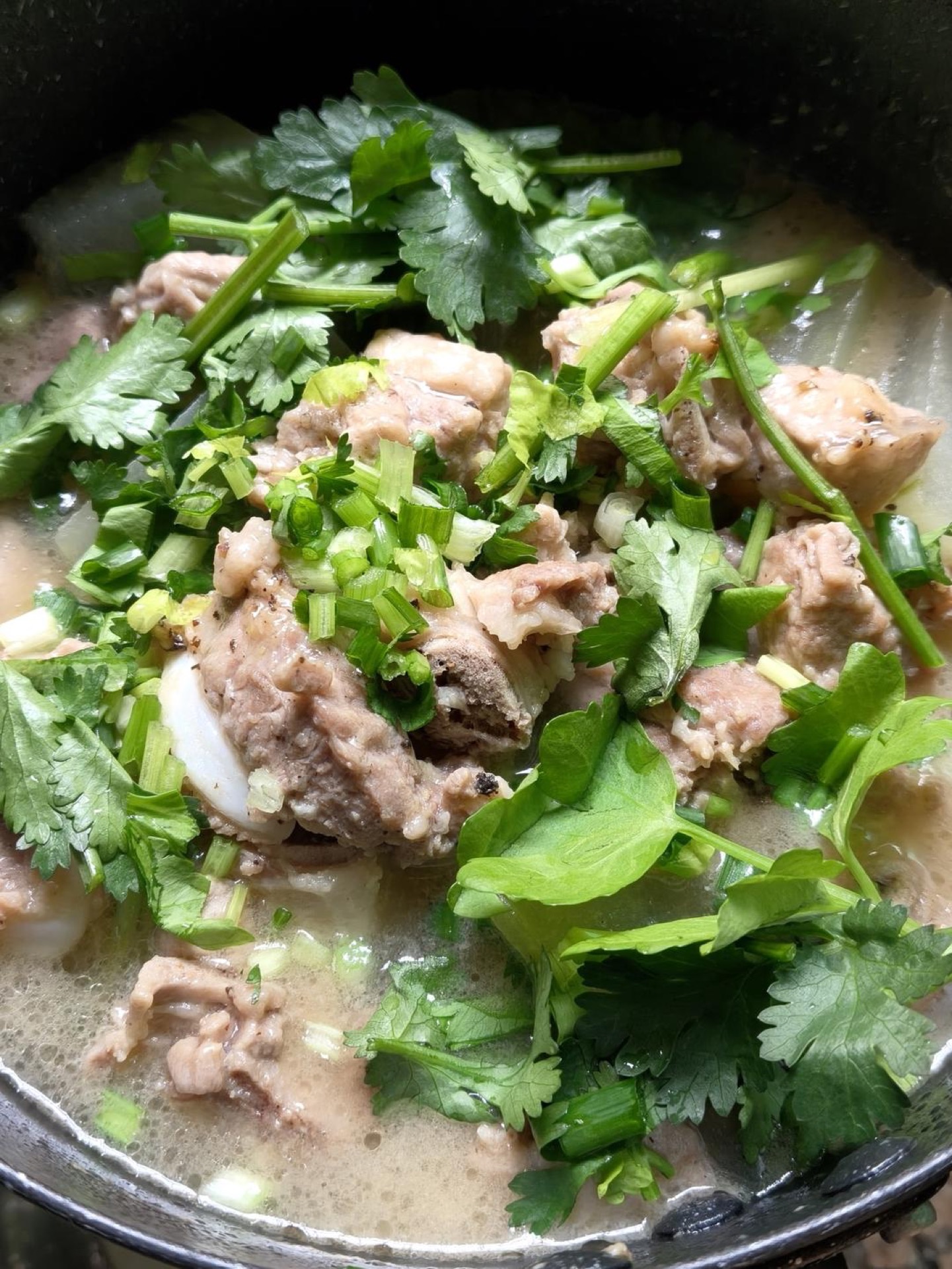 Winter melon pork rib pot in a snow pan, with tender ribs over translucent winter melon and fresh herbs on top