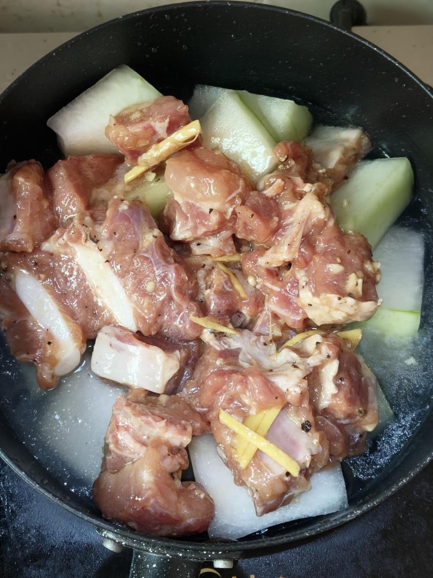 Lay the winter melon slices in an even layer in the bottom of a snow pan or small pot, pour in one bowl of water, spread the marinated ribs flat on top, then bring it to a boil ove