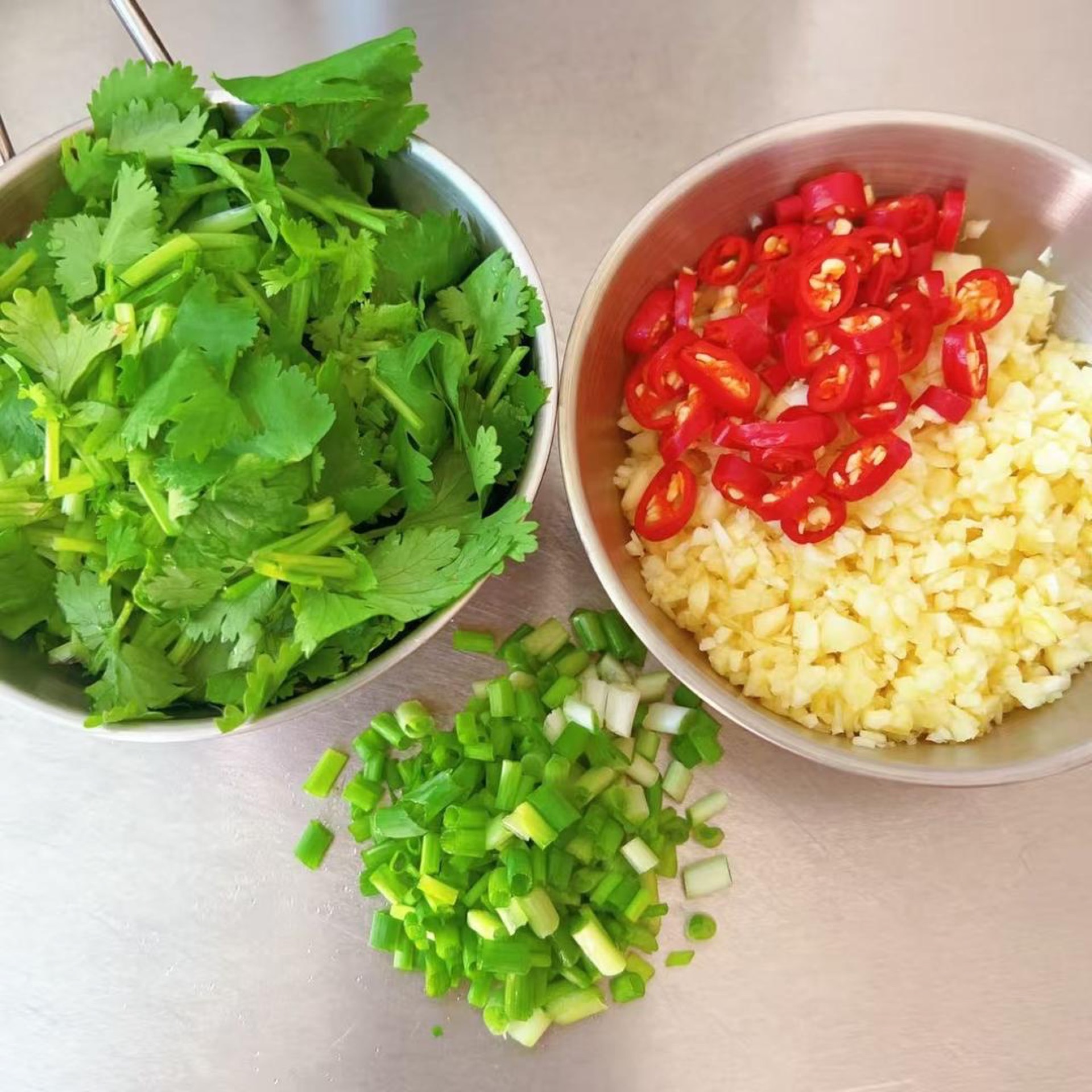 Prepare the minced garlic, chopped scallions, sliced bird's eye chili, and chopped cilantro.